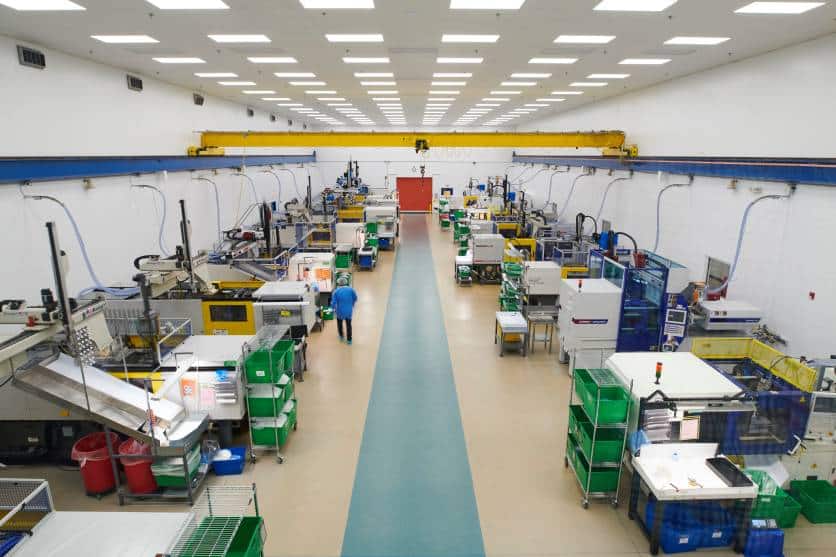 Wide-angle view of a brightly lit, organized cleanroom manufacturing floor with multiple injection molding machines and workstations showcasing BMP's cleanroom manufacturing capabilities.