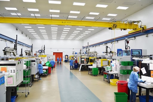 Clean, brightly lit manufacturing floor at BMP Medical with technicians operating injection molding machines and assembling medical components.