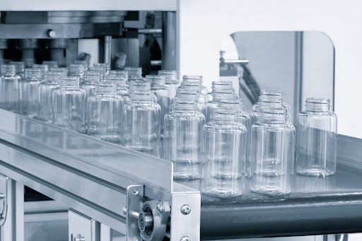 Clear plastic bottles moving along an automated conveyor system during the manufacturing process.